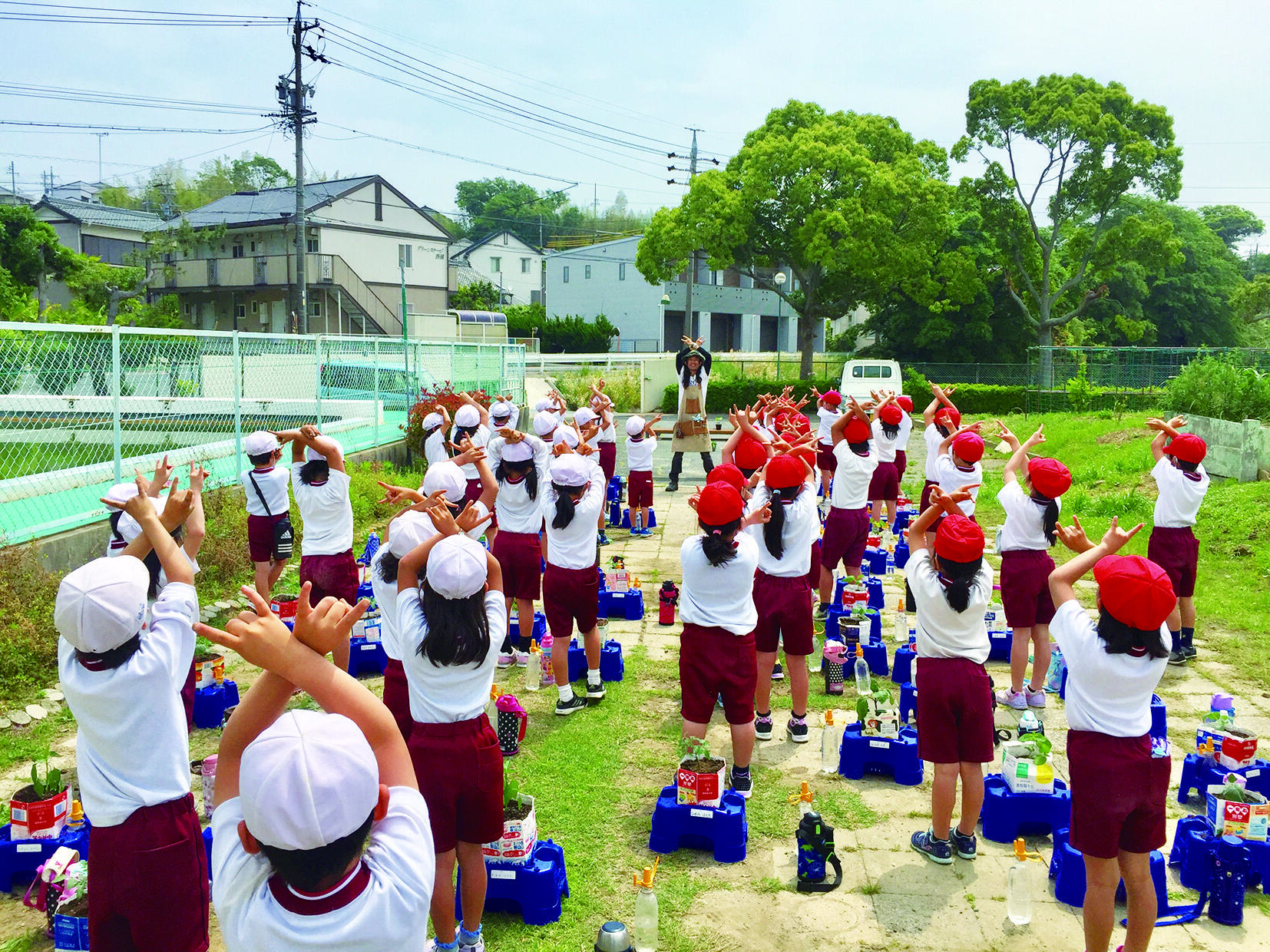 小学校での花育の様子。子どもたちと一緒に「マキシマムザ店長」のポーズ
