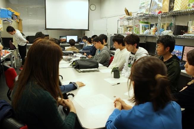 プロジェクトの主旨説明資料に見入る学生ら