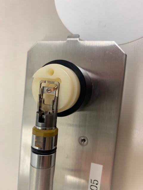 強化2軸ホルダーの先端部の写真 観察装置R005に挿入する強化2軸ホルダーの先端部の写真です。ホルダーの先端部に試料を設置する部分があり、ピンセットで試料を円形部分にセットしてスペーサで試料を固定しています。