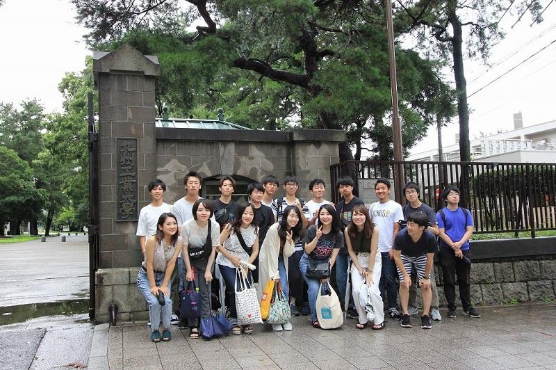 九州工業大学の正門前で記念撮影
