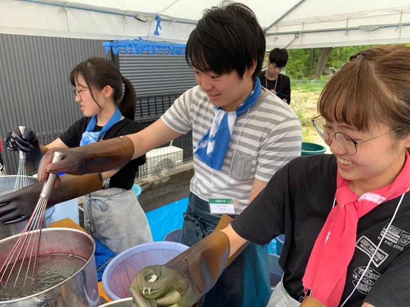 染色するために布を煮詰める学生達