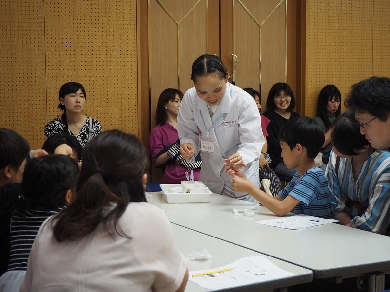 おくすり１１０番メンバーが補助し、小学生が体験実験を行っている様子