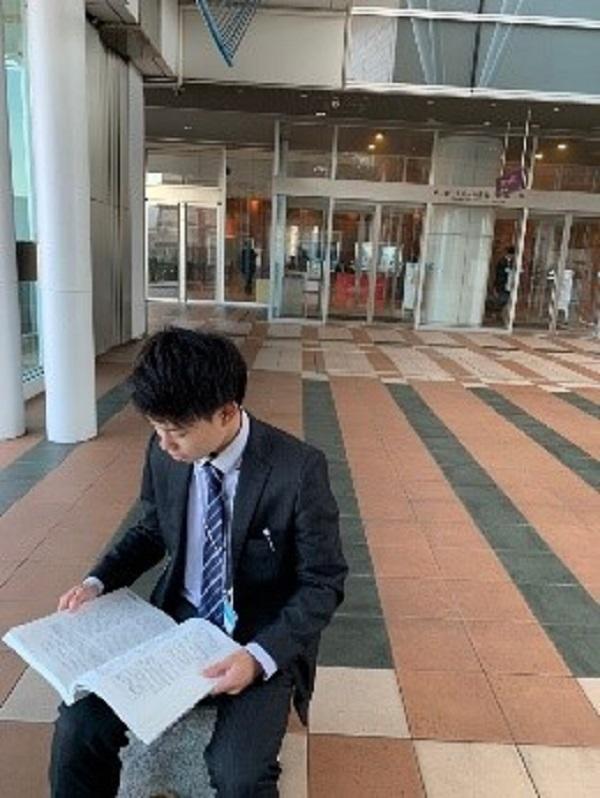 会場の椅子に座り、寄稿集を読んでいる様子。企業や大学の発表に関する論文を事前に読無ことで、より深く発表を理解することができた。