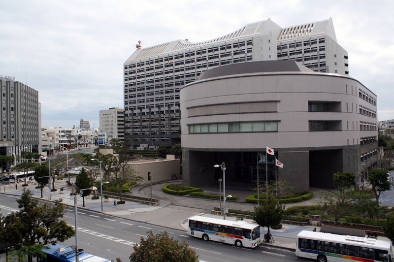 沖縄県行政の中枢である沖縄県庁舎。設計は黒川紀章で隣には県議会、県警察本部庁舎が、近くには那覇市役所やテレビ局、百貨店、銀行などが立ち並びます。