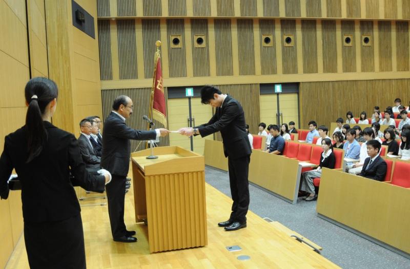 吉久光一学長(左)から決定通知書を受け取る人間学部4年の髙橋那夏さん