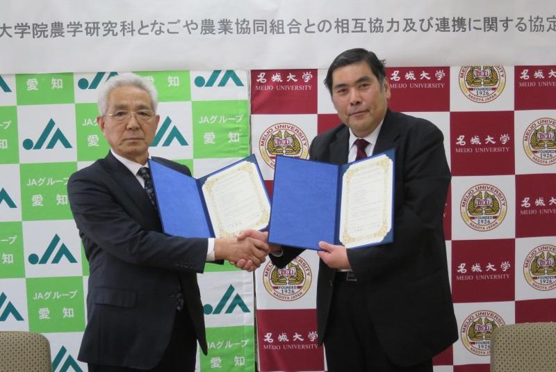 協定書を手に握手する小原章裕農学部長・大学院農学研究科長(右)と二村文昭組合長