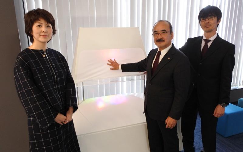 モニュメント「七色の光波」と一緒に写真に納まる吉久学長(中)、生田准教授(左)、竹内教授