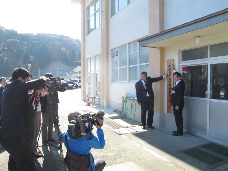 報道陣の前で名城大学氷見市連携推進センターの看板を掛ける小原学部長と林市長