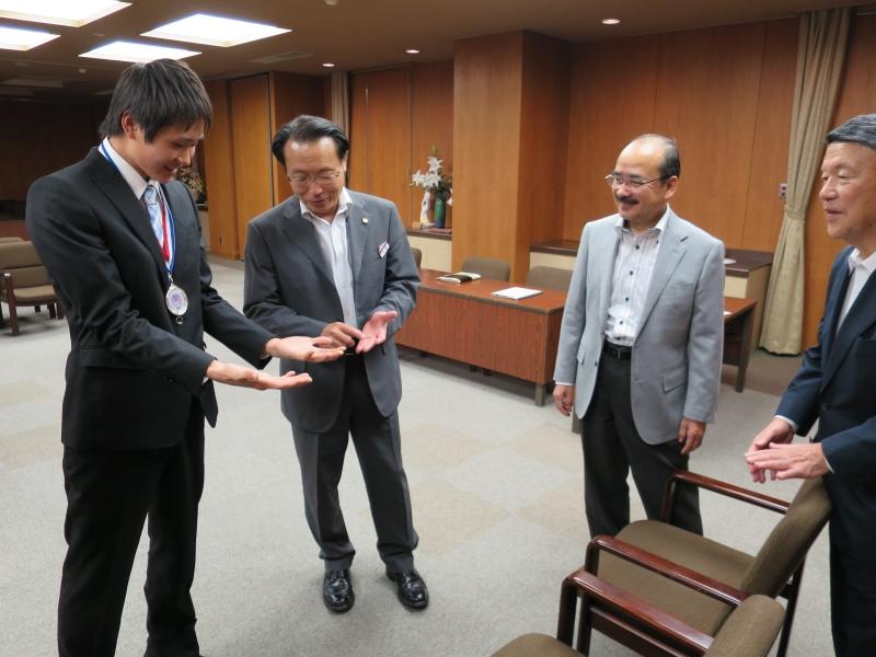 吉久学長（右から2人目）らに手を見せる亀山さん（左端）