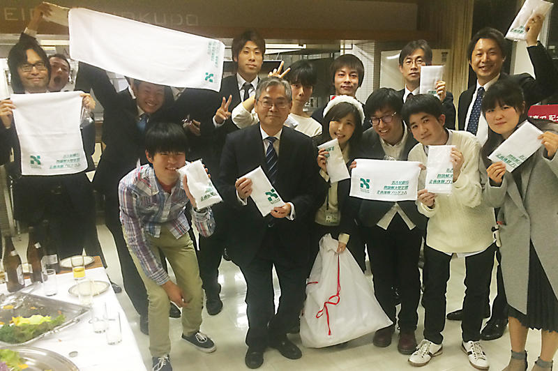 名古屋銀行の中村昌弘頭取(中央)と同企画の記念タオルを手に記念撮影する本学学生と中京大学の学生