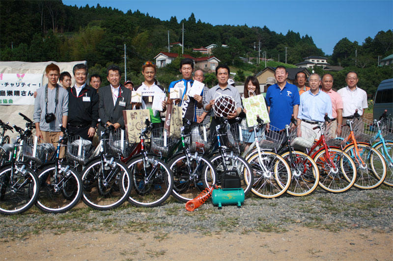 大島観光協会横の広場で行われた贈呈式に臨んだ山本さん、中島さんと関係者たち