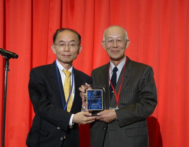 JSNPの山脇成人理事長（広島大学大学院医療薬学総合研究科、左）から楯を受け取る鍋島特任教授