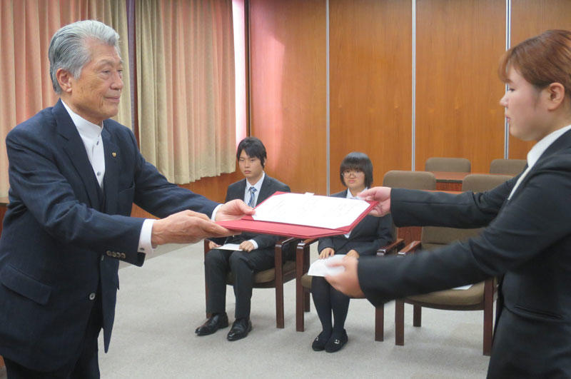 奨学生決定通知書を手渡す長谷川士郎氏(左)