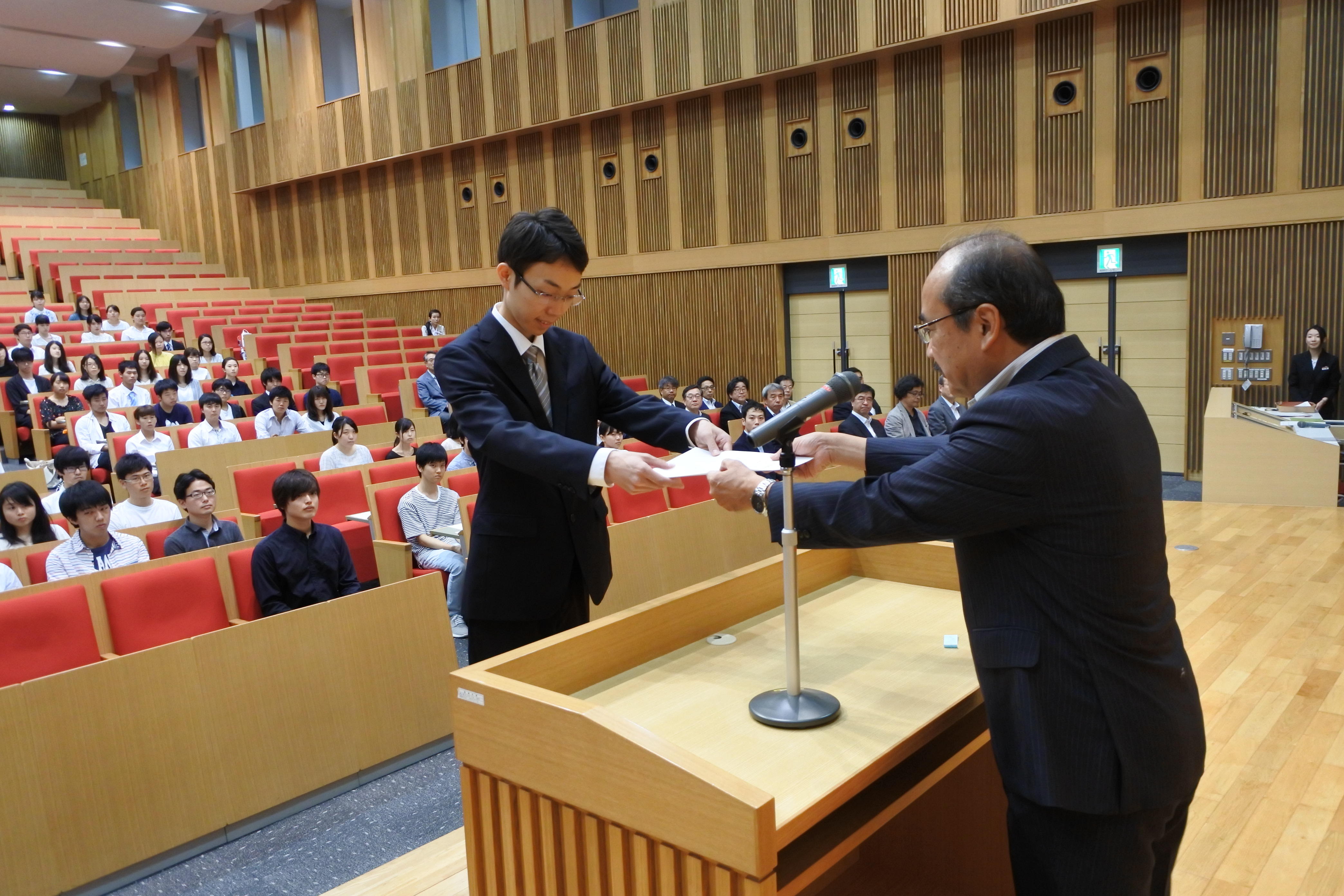 吉久光一学長(右)から学業優秀奨学生決定通知書を受ける保木翔太さん