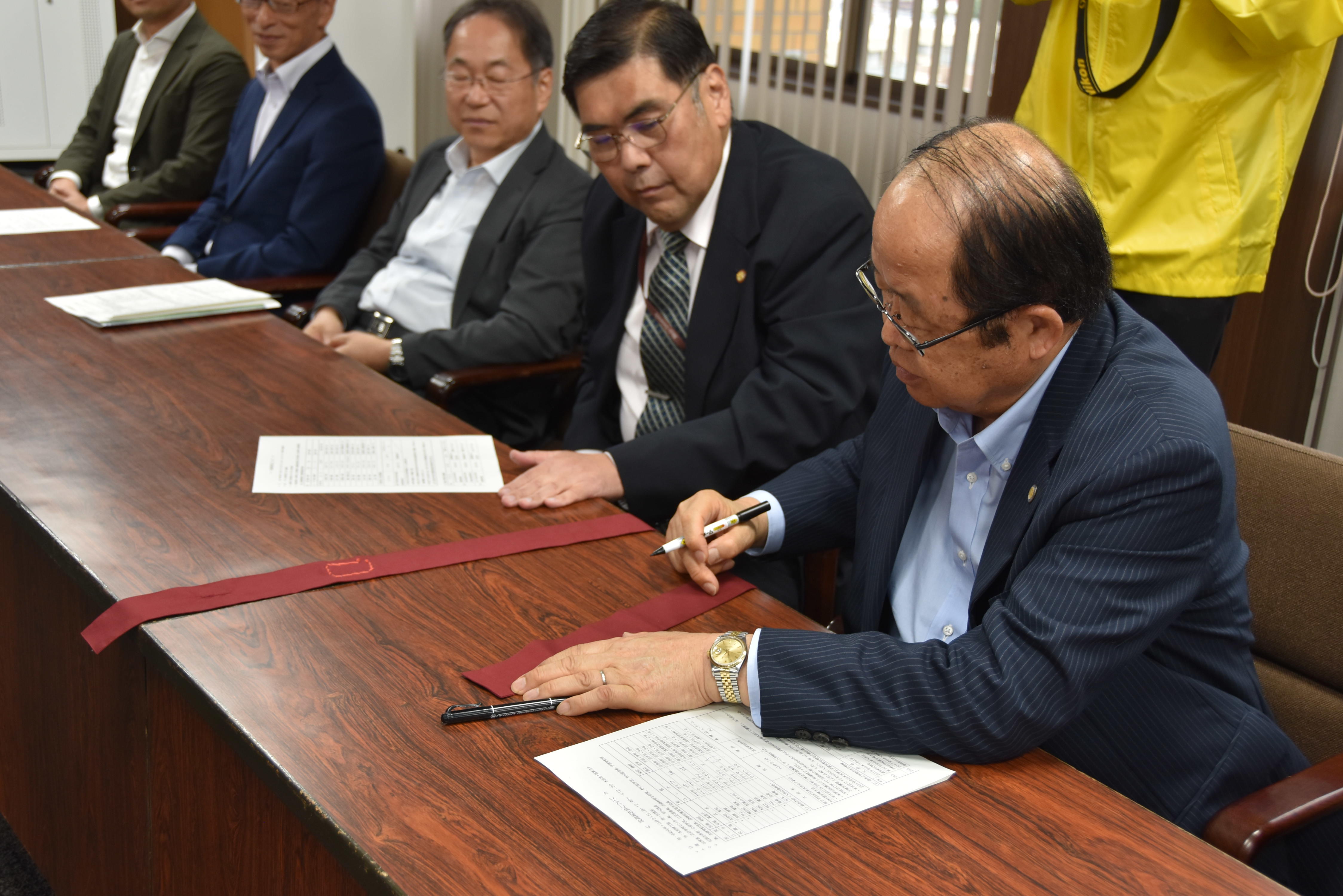 たすきにメッセージを書き込む立花理事長