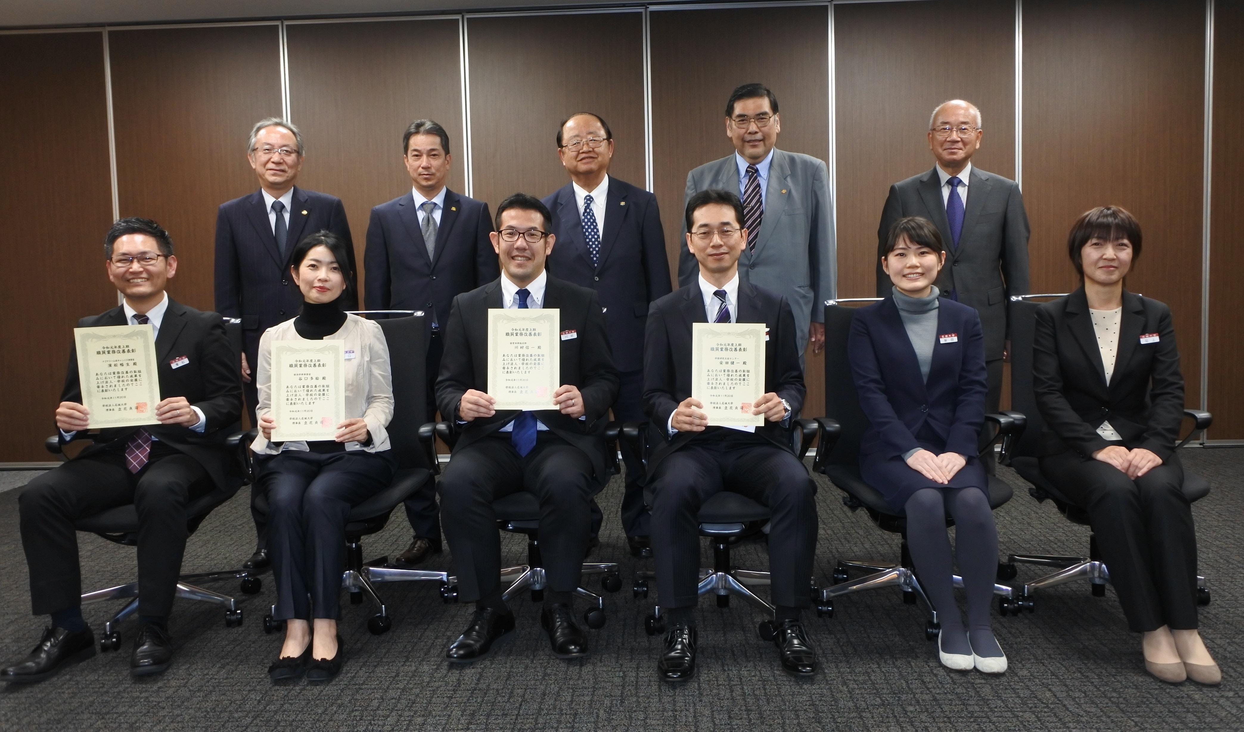 表彰状を手にする職員と立花貞司理事長ら
