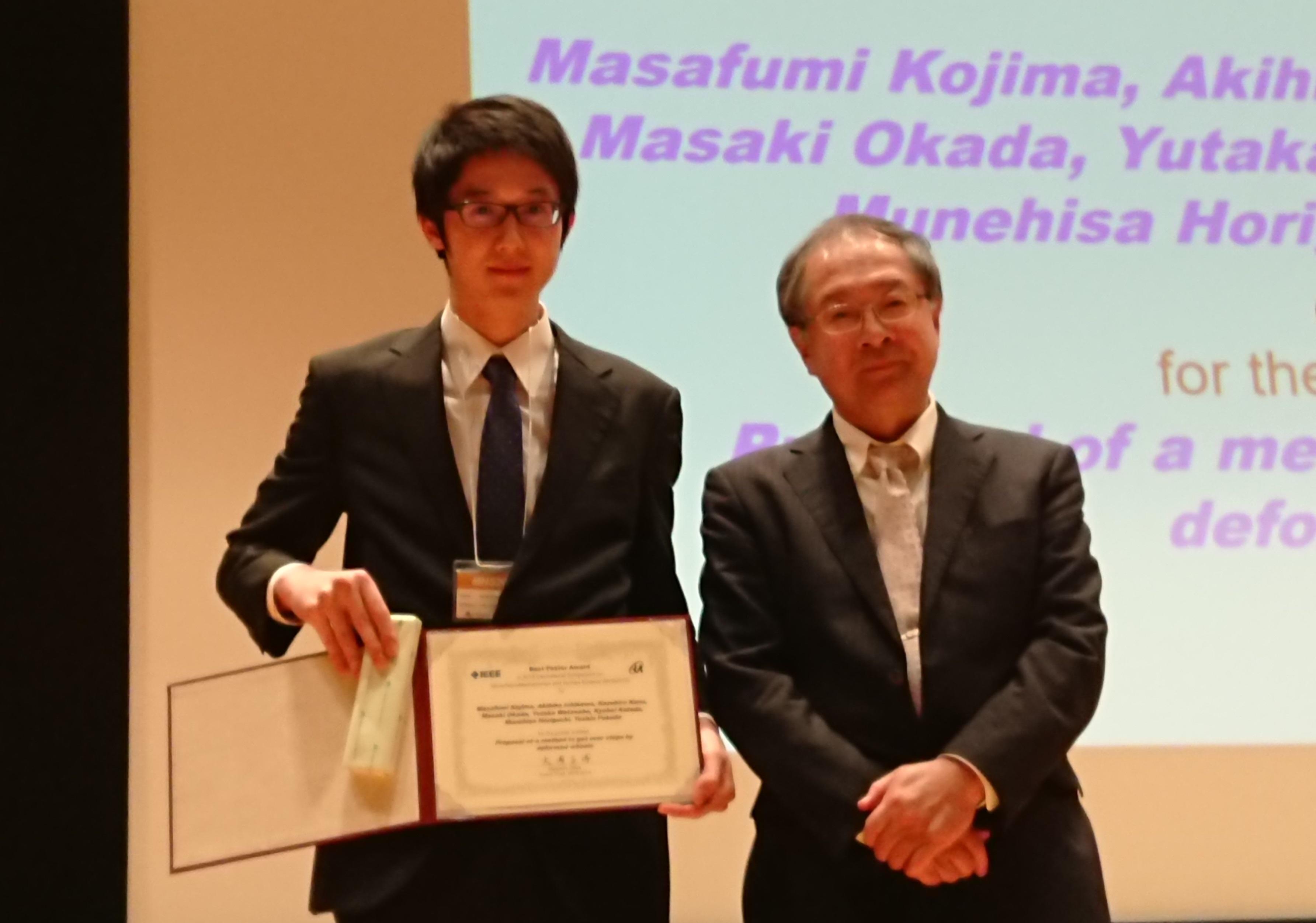 表彰状を手にする小嶋さん。右は審査委員長の大岡昌博名古屋大学教授