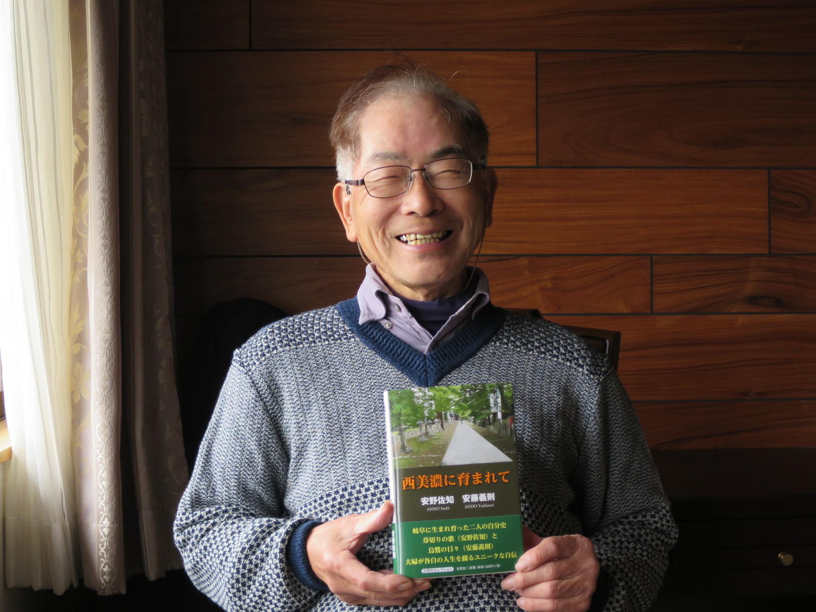 岐阜県海津市の自宅で自分史を手にする安藤義則名誉教授