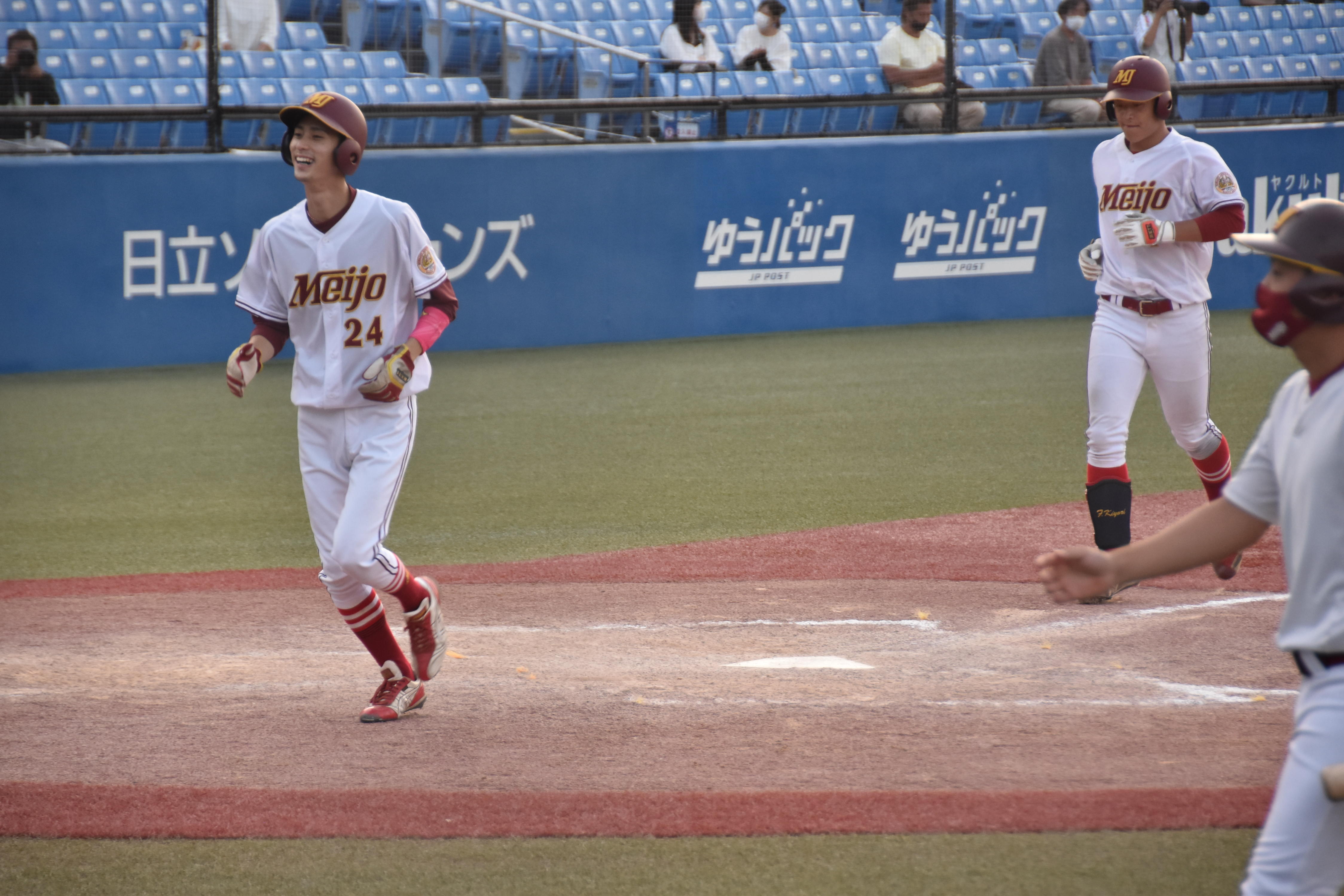 九回の追い上げ。2点本塁打を放ち、藤原連太郎選手（人間学部4年）（左、24番）に続いてホームに還る藤田希和選手（法学部3年）=東京の神宮球場で