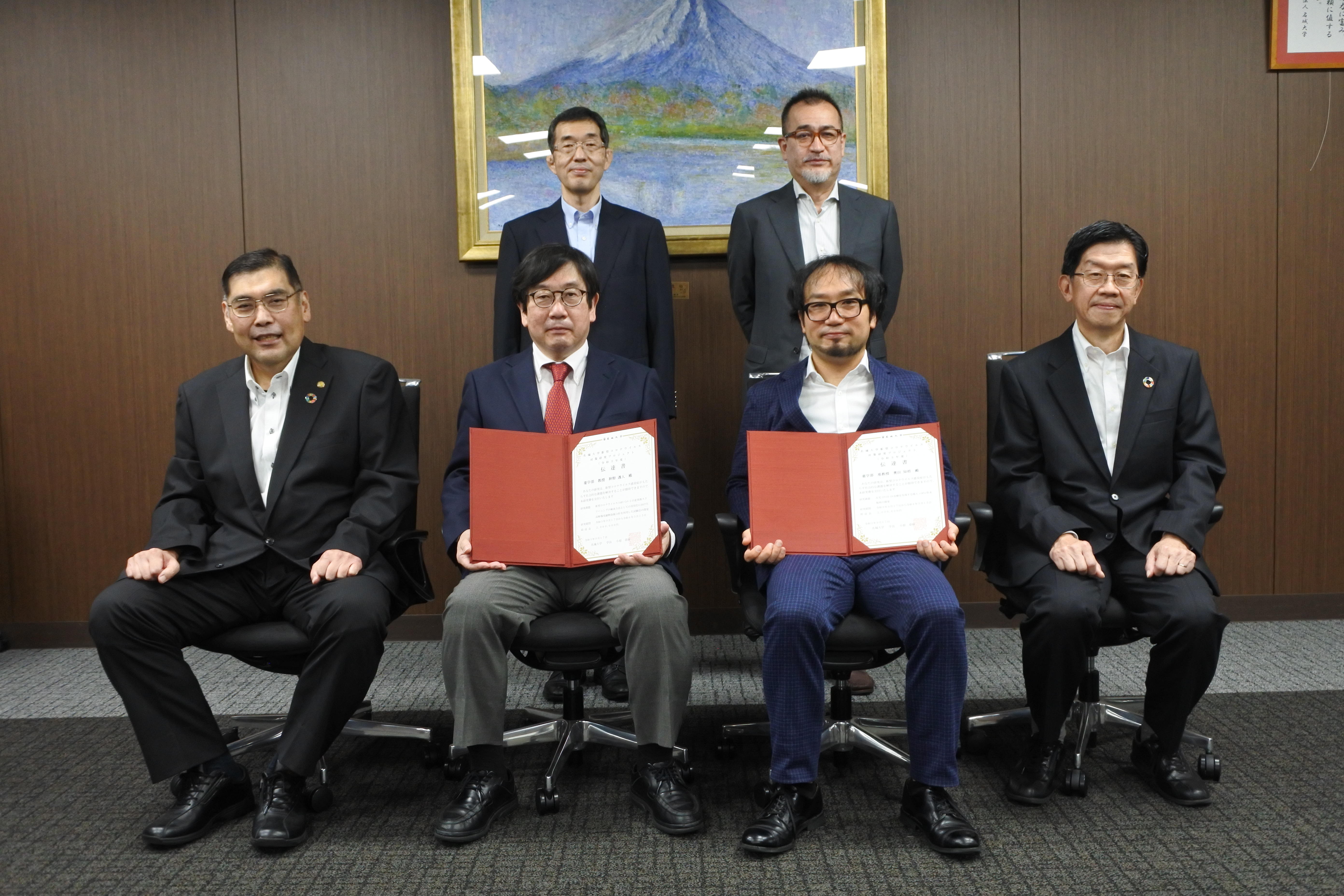 プロジェクトの伝達書を手にする神野透人教授（前列左から2人目）と奥田知将准教授（同3人目）