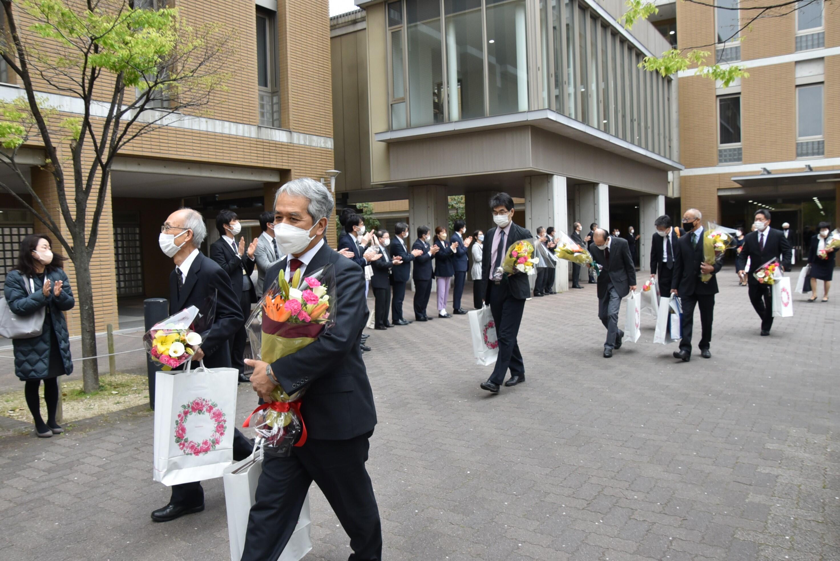 教職員に見送られてキャンパスを去る定年退職者の皆さん