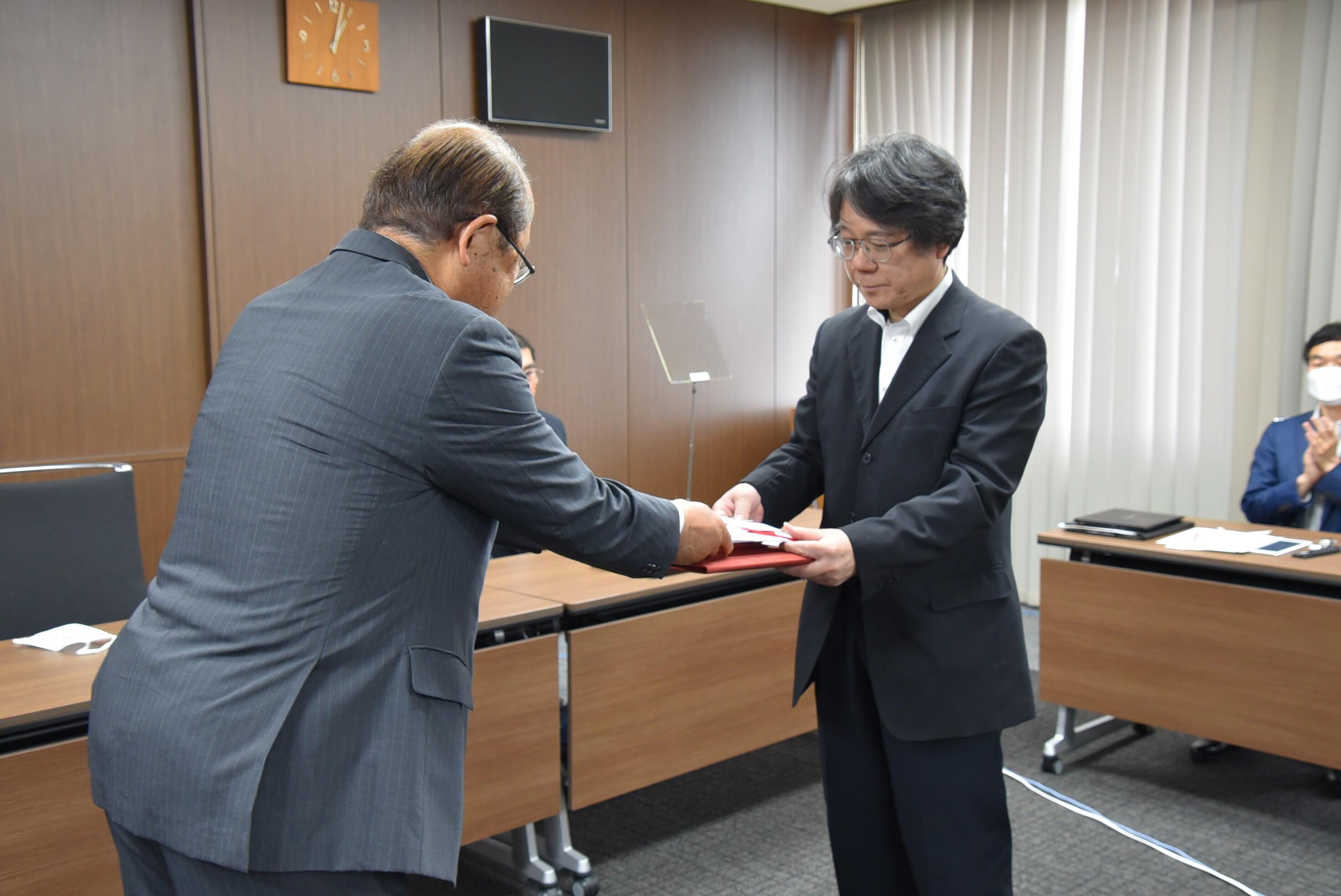 立花理事長（左）から賞状と目録を受け取る齊藤教授