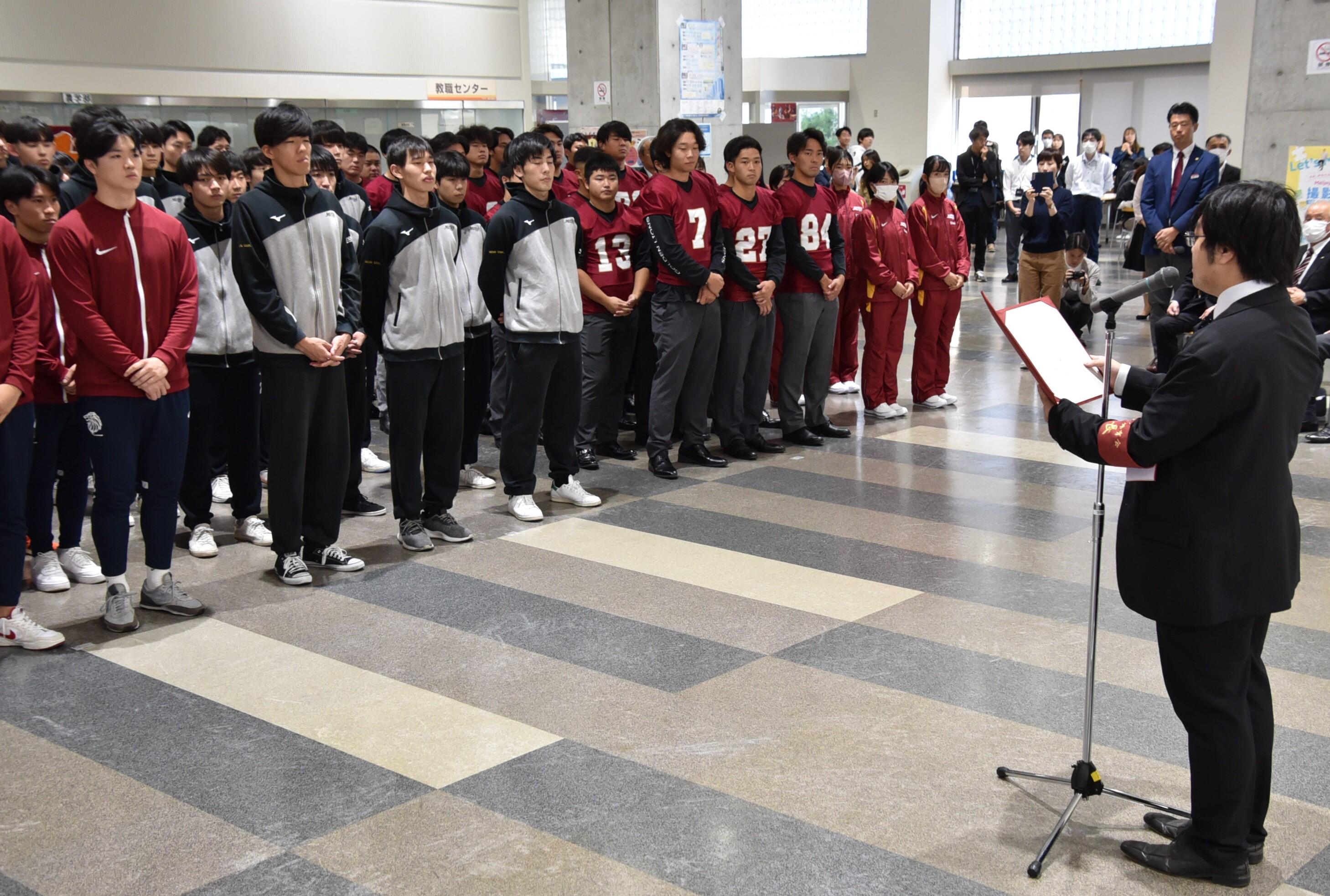 あいさつする体育会の梅村会長（右）