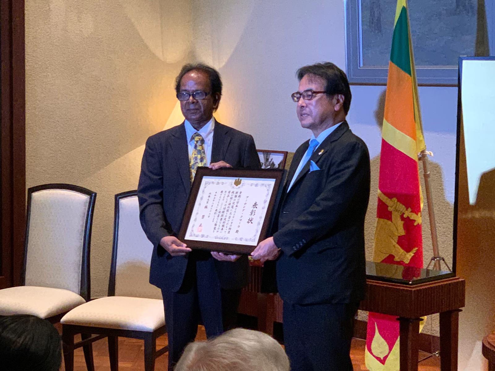9月15日に在スリランカ日本大使公邸で水越英明大使から賞状を受け取るクマーラ名誉教授（左）