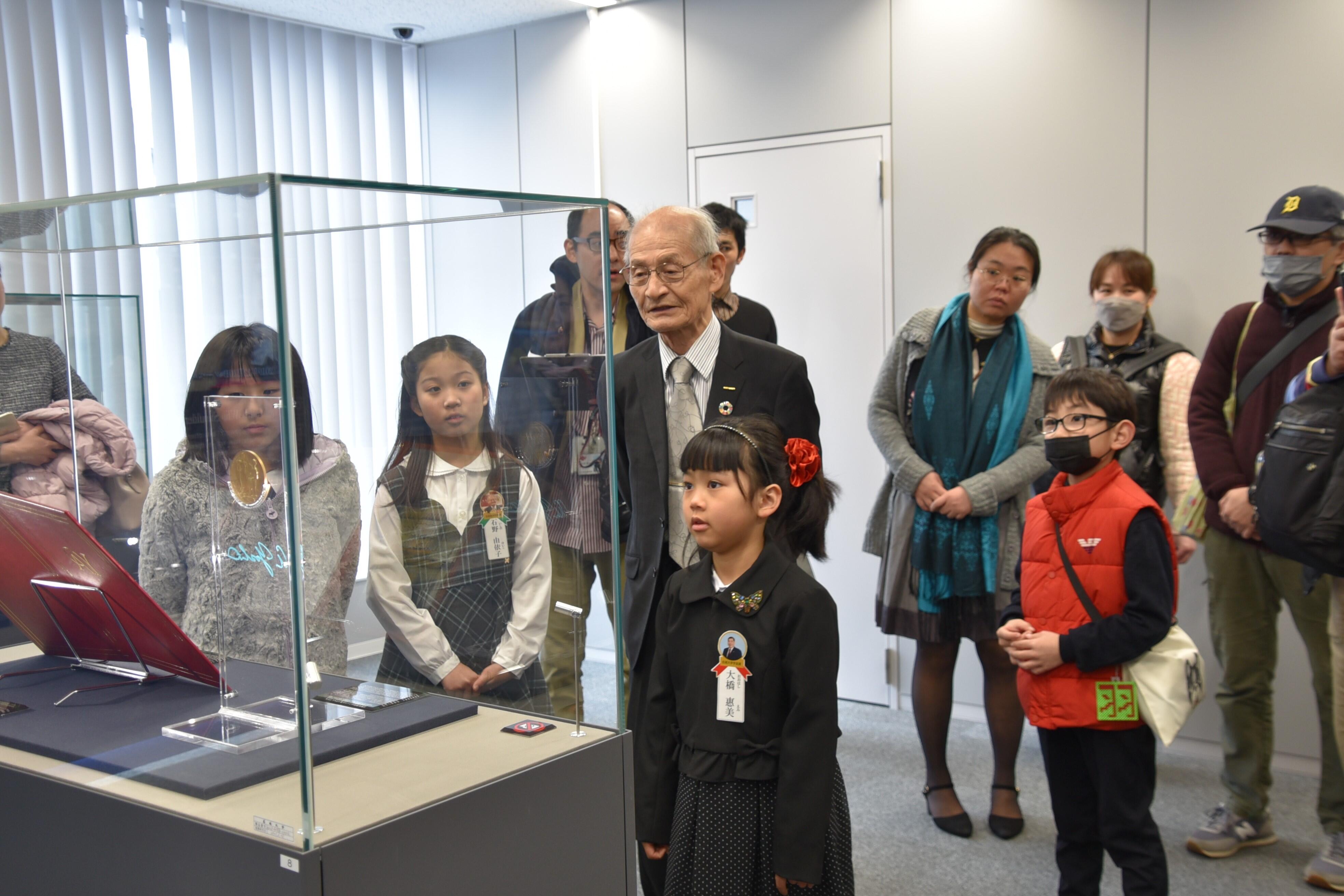 吉野終身教授と一緒にノーベル賞のメダルのレプリカを見る受賞者