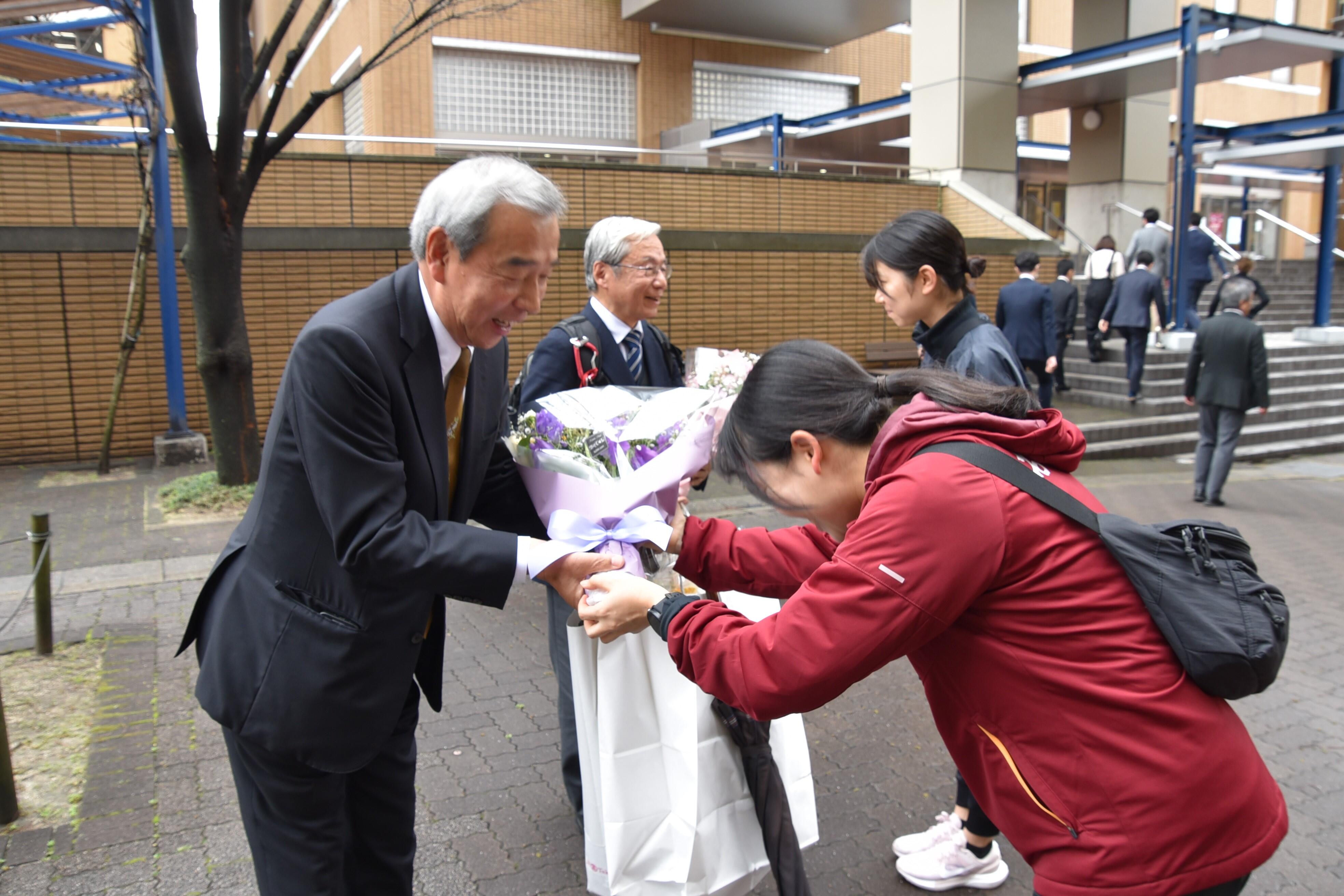 女子駅伝部員から花束を贈られる加鳥教授と薬学部の豊田行康准教授