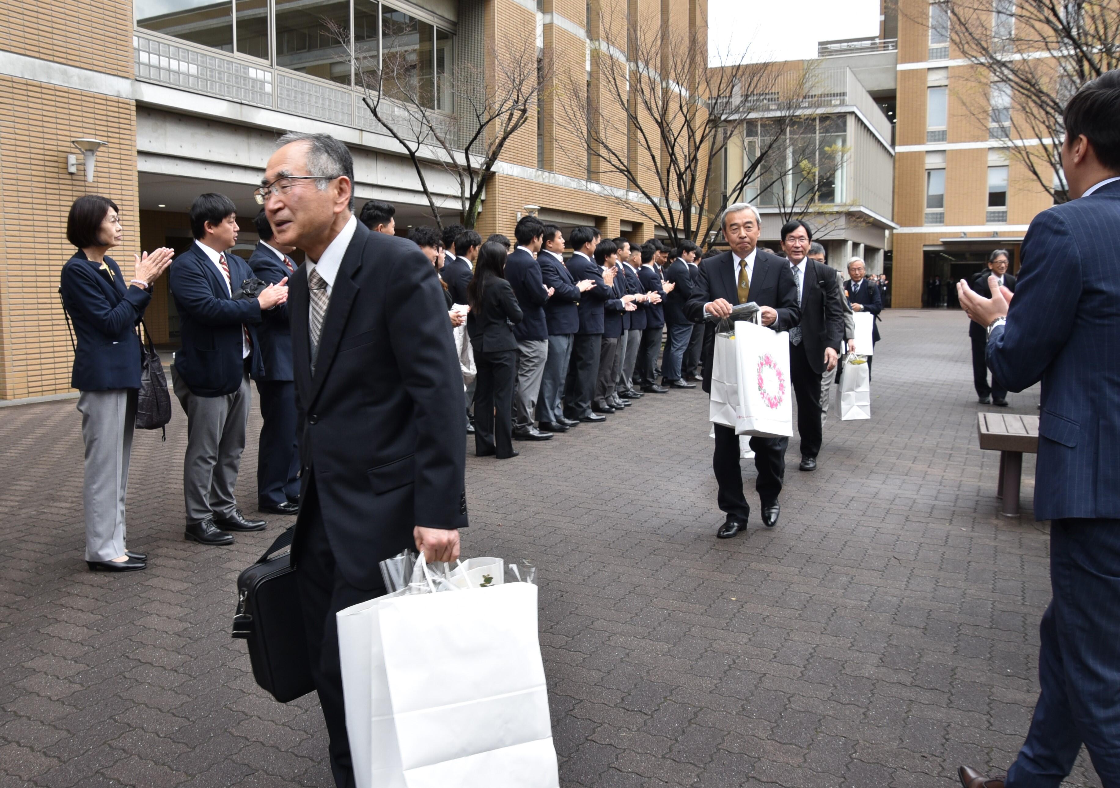 教職員や学生に見送られてキャンパスを去る退職者の皆さん