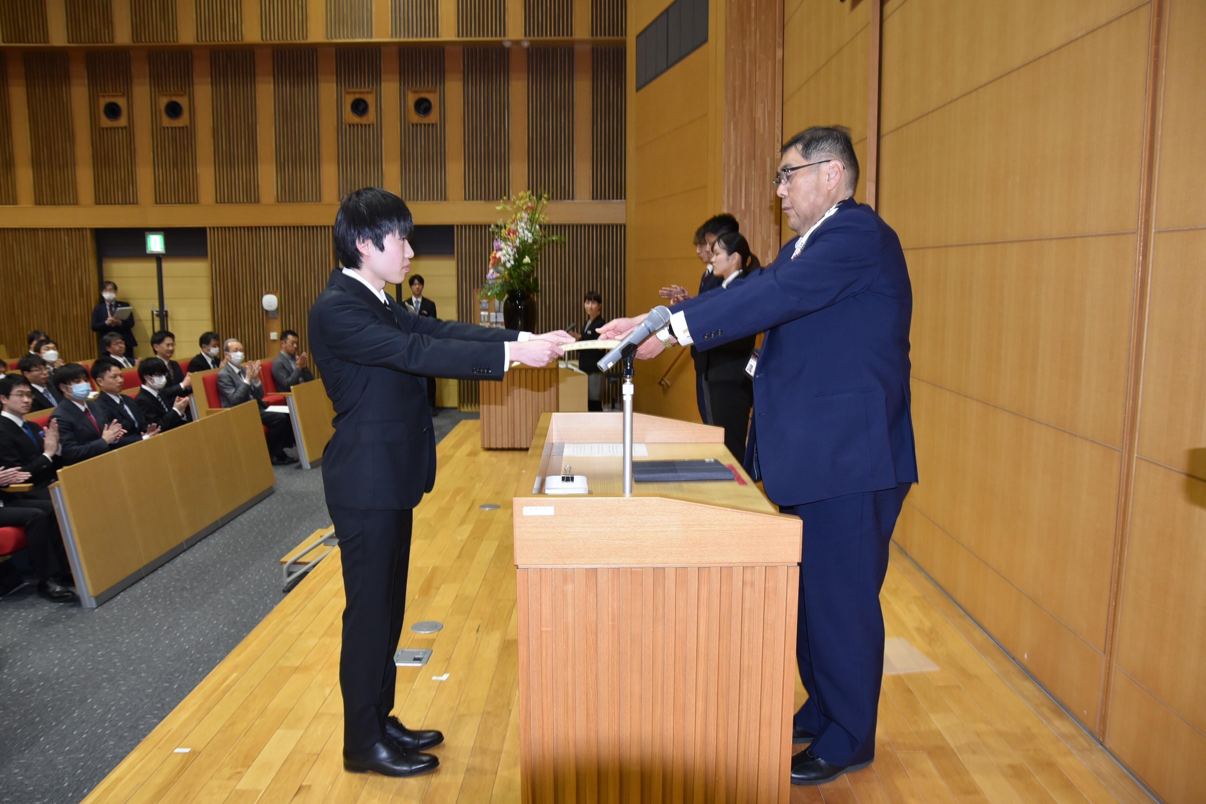 優秀表彰の表彰状を受け取る「ロボット倶楽部」の吉井智哉さん（理工学部４年）