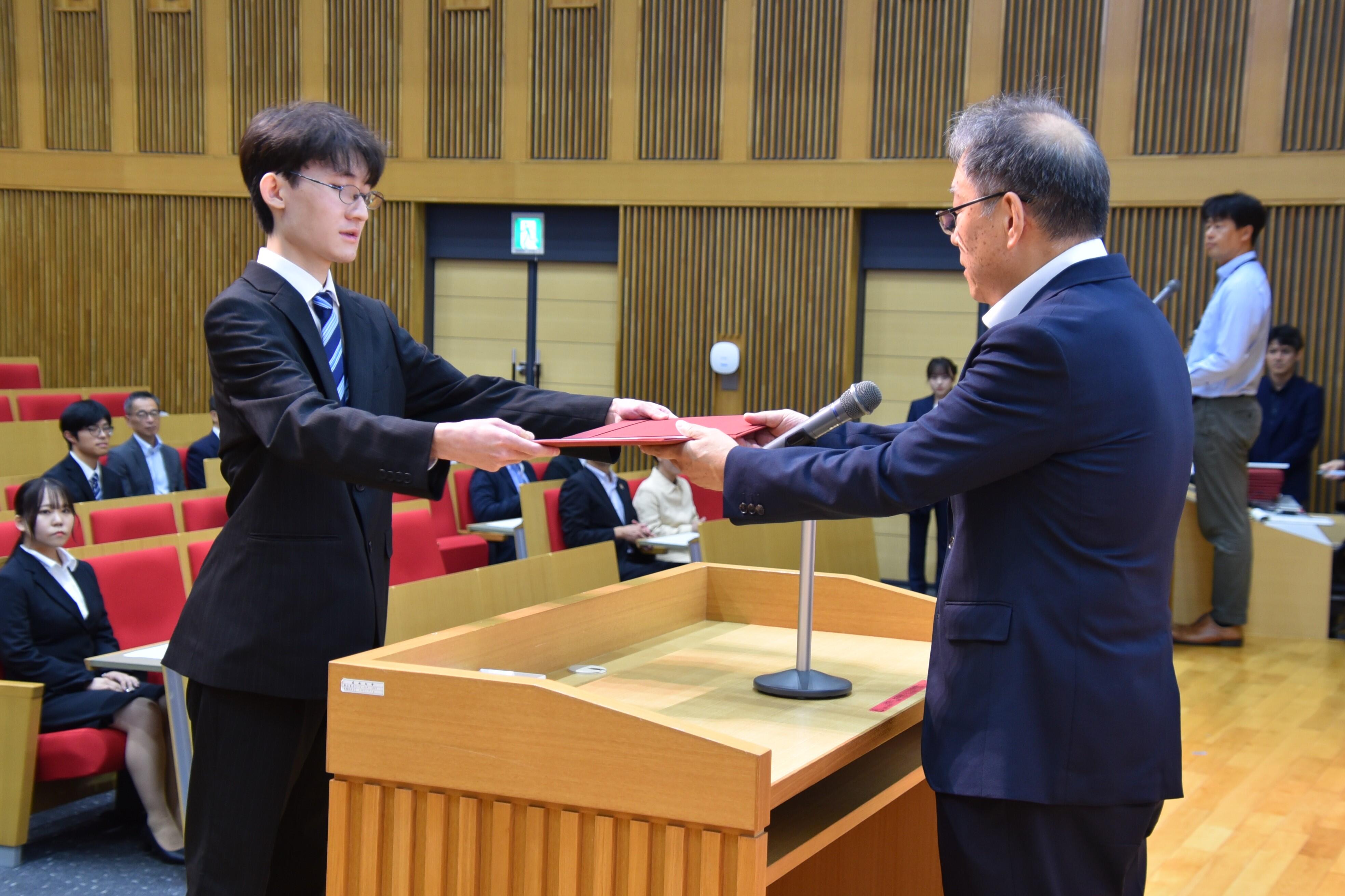 野口学長から学業優秀奨学生の決定通知を受け取る青栁さん