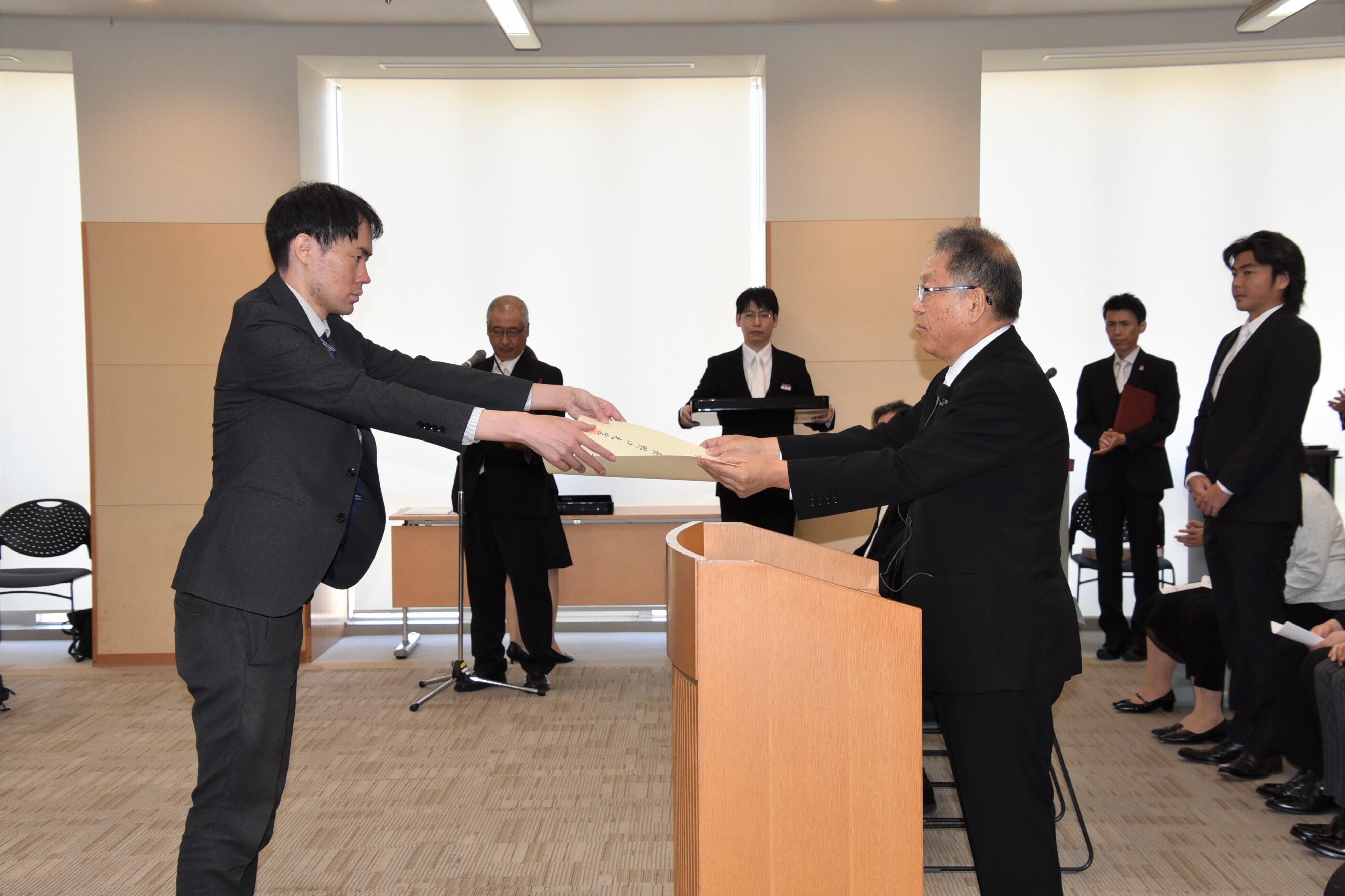 野口学長から学位記を手渡される丸尾さん（左）