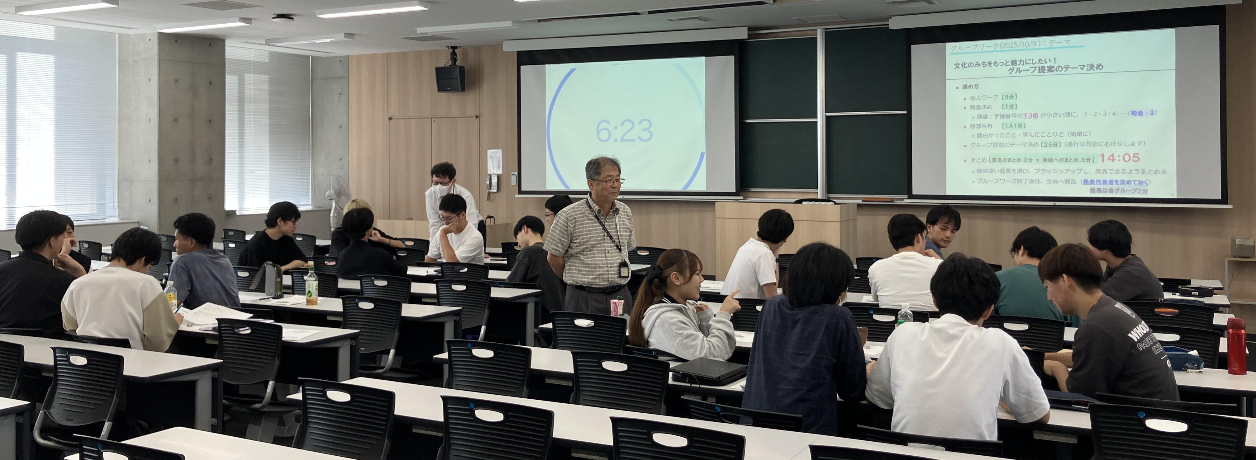 グループごとに議論する学生たちと成り行きを見守る教員