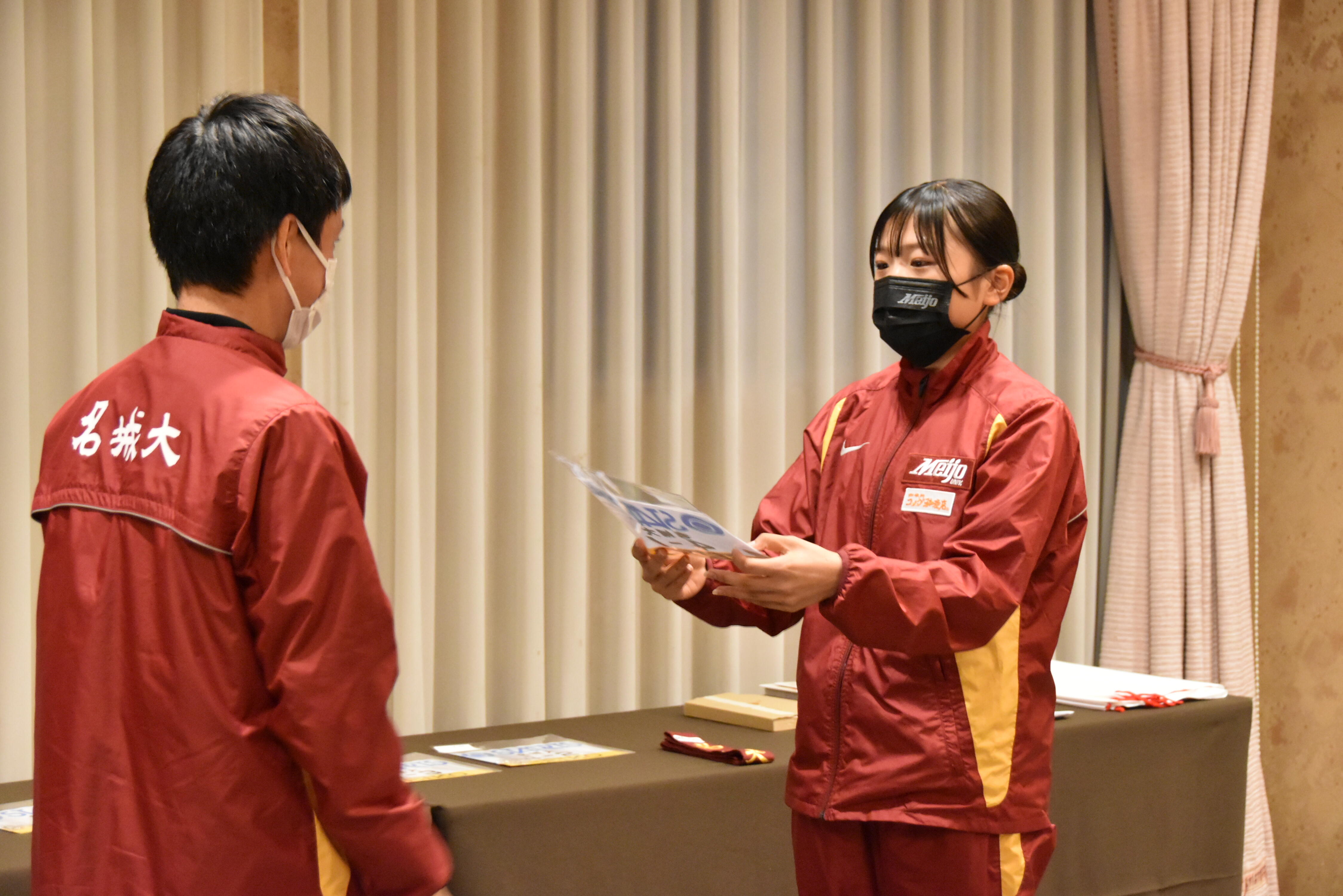 矢嶋部長からゼッケンを受け取る細見選手
