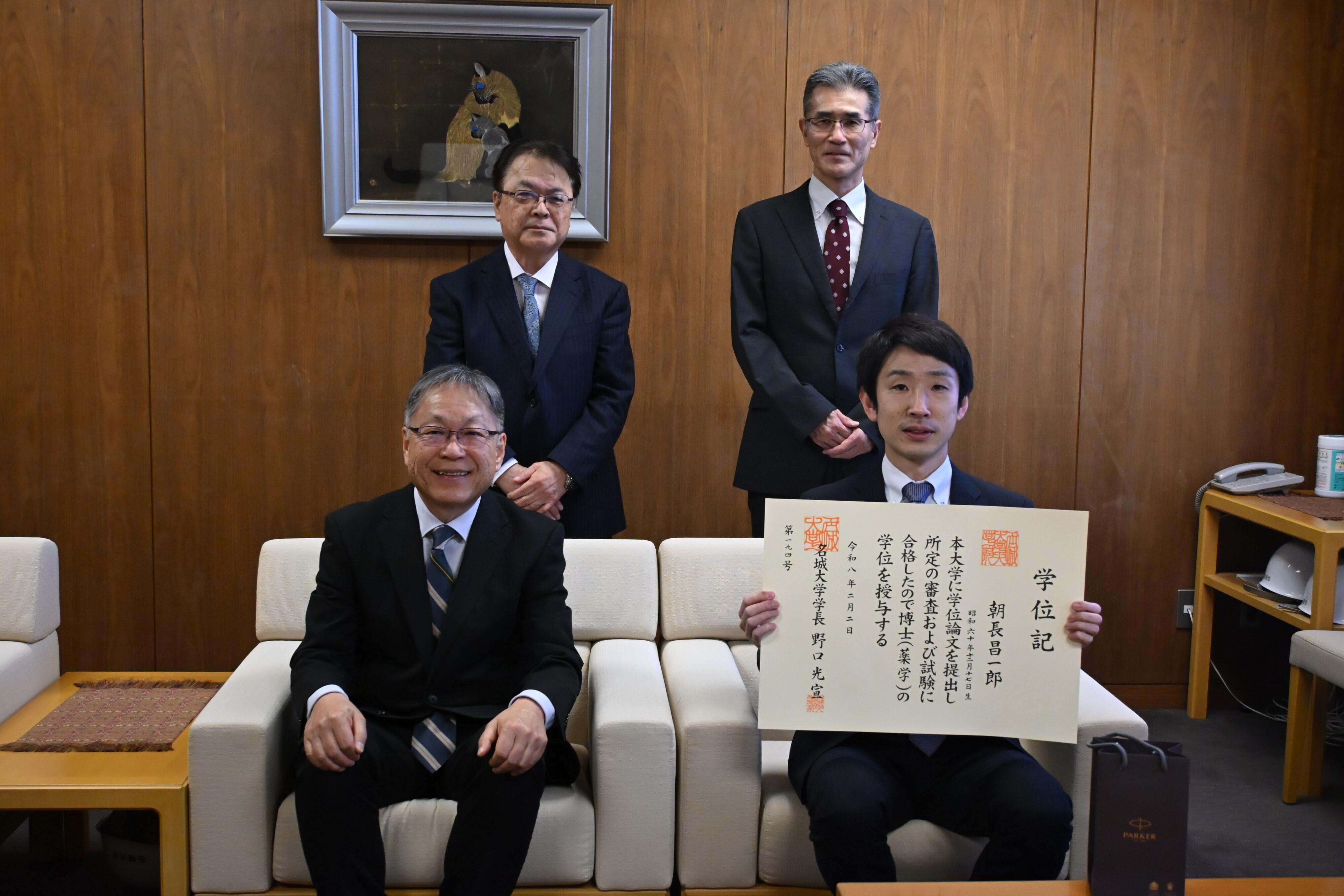 博士（薬学）の学位記を手にする朝長さん（前列右）と野口学長（同左）、（後列左から）亀井研究科長、論文主査の北垣教授