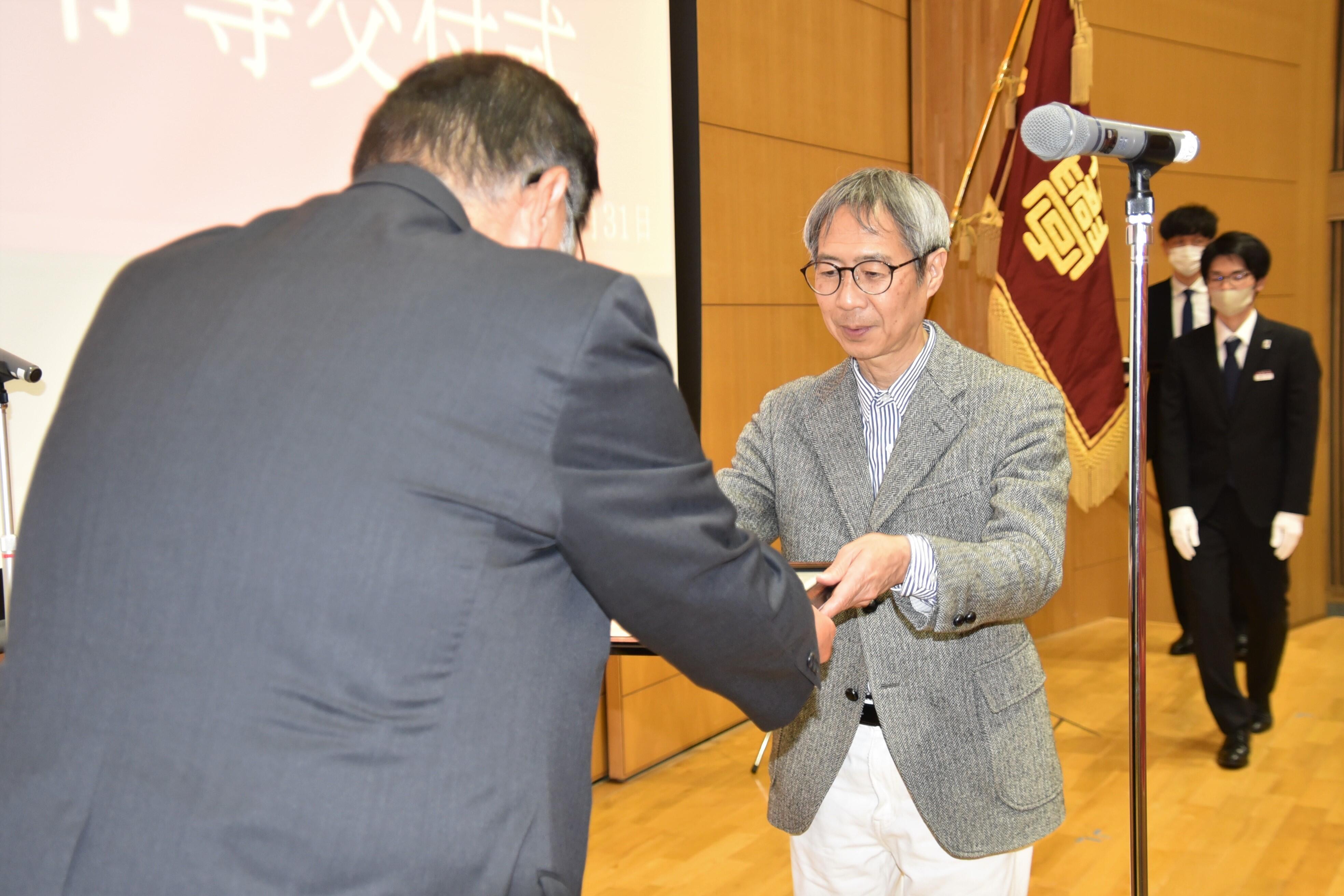 小原理事長から感謝状を受け取る経営学部の堀川新吾教授