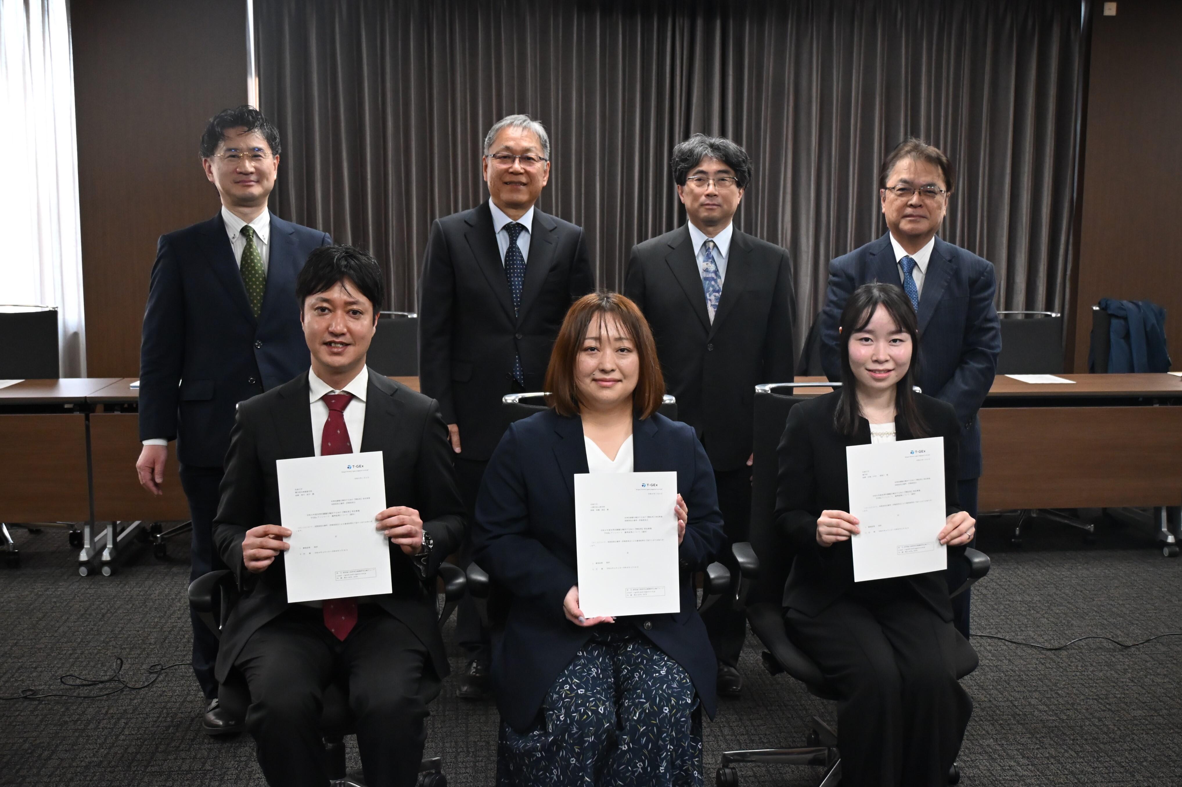 T-GExアソシエート採択通知書を手にする前列左から黒川助教、髙橋助教、河地助教、後列左から氏田農学部長、野口学長、笠井人間学部長、亀井薬学部長