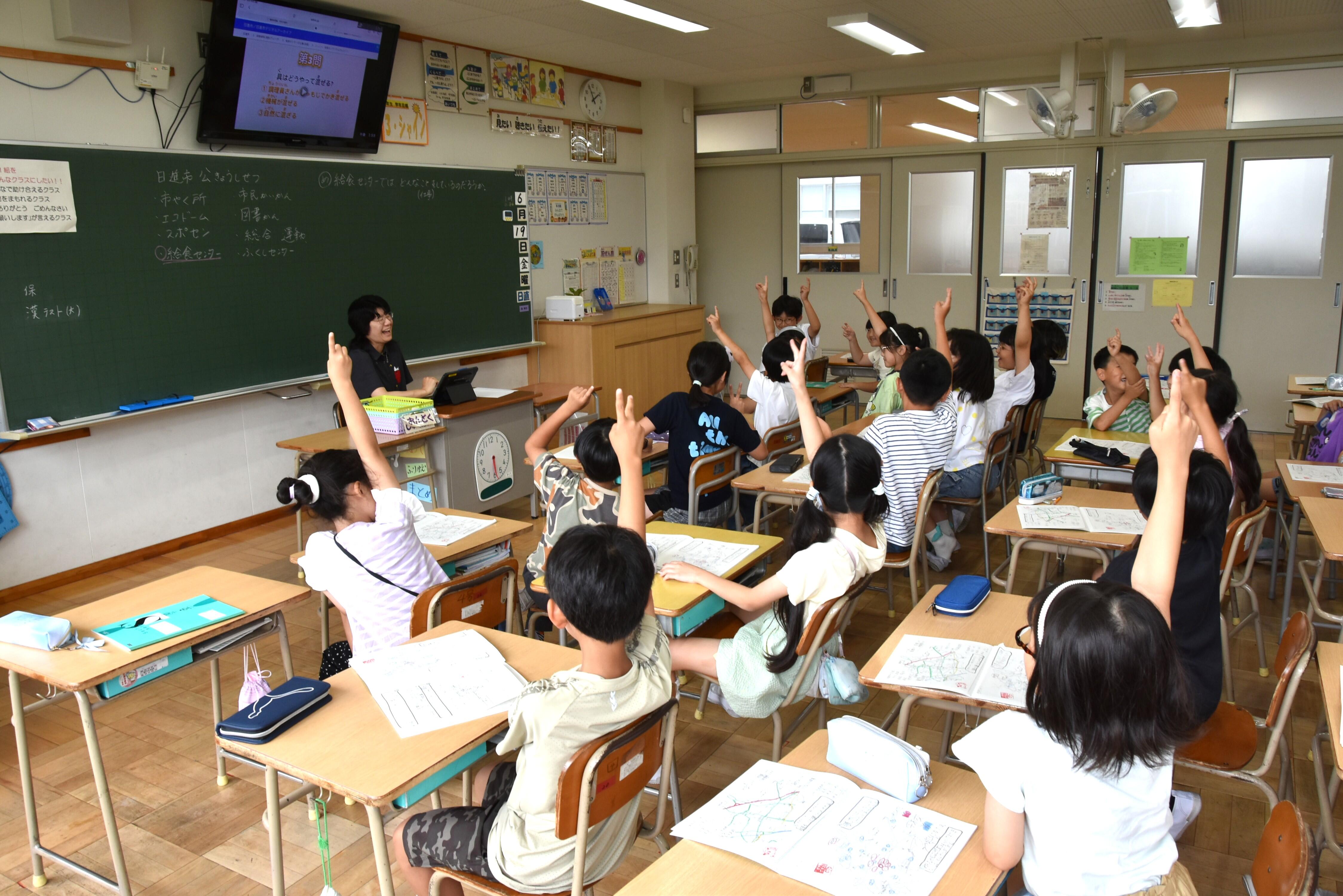 クイズで正解だと思う番号に元気よく手を挙げる児童たち