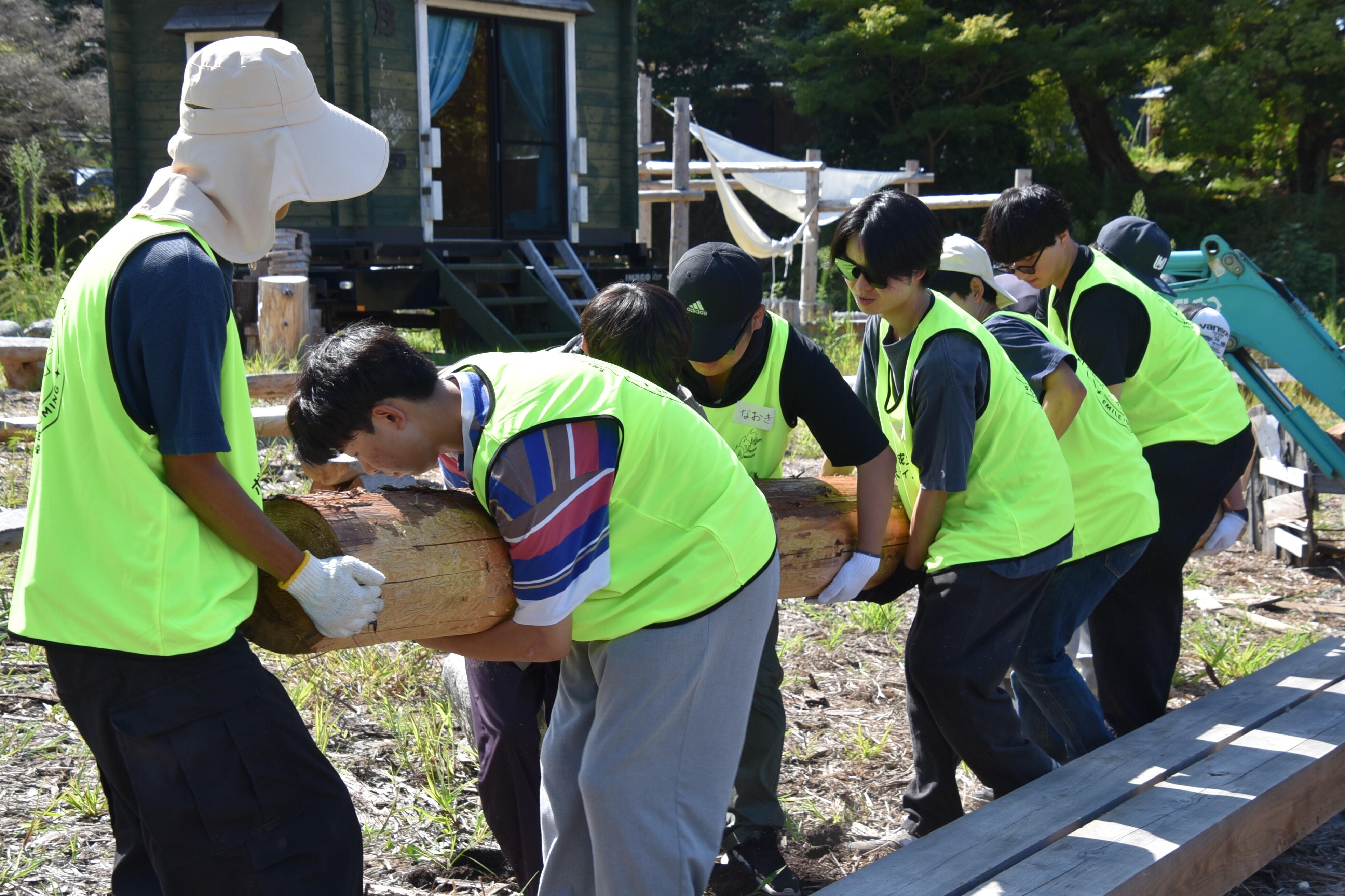 重い丸太を協力して運ぶ