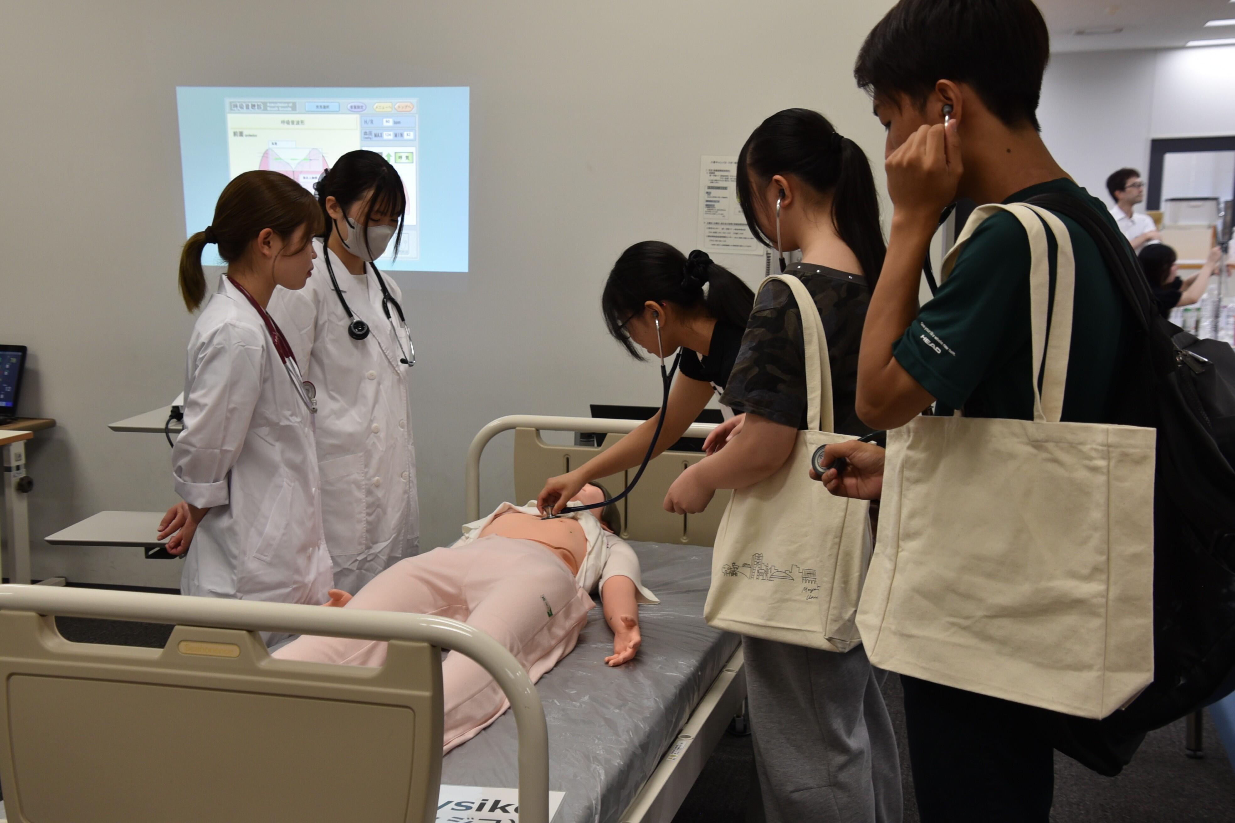薬学部の体験コーナーで聴診器を使う来場者