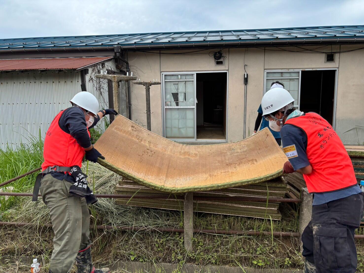 水を吸って重くなった畳を運ぶ学生たち