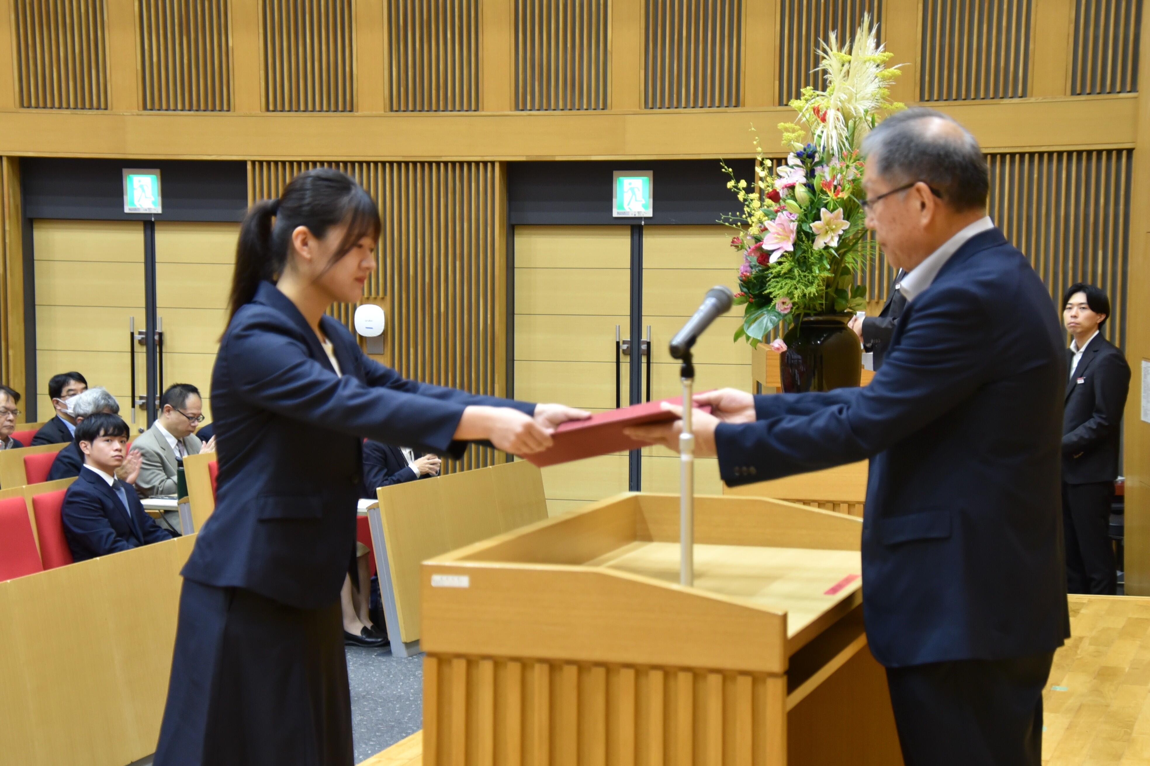 学業優秀奨励者を代表して決定通知を受け取る田中さん