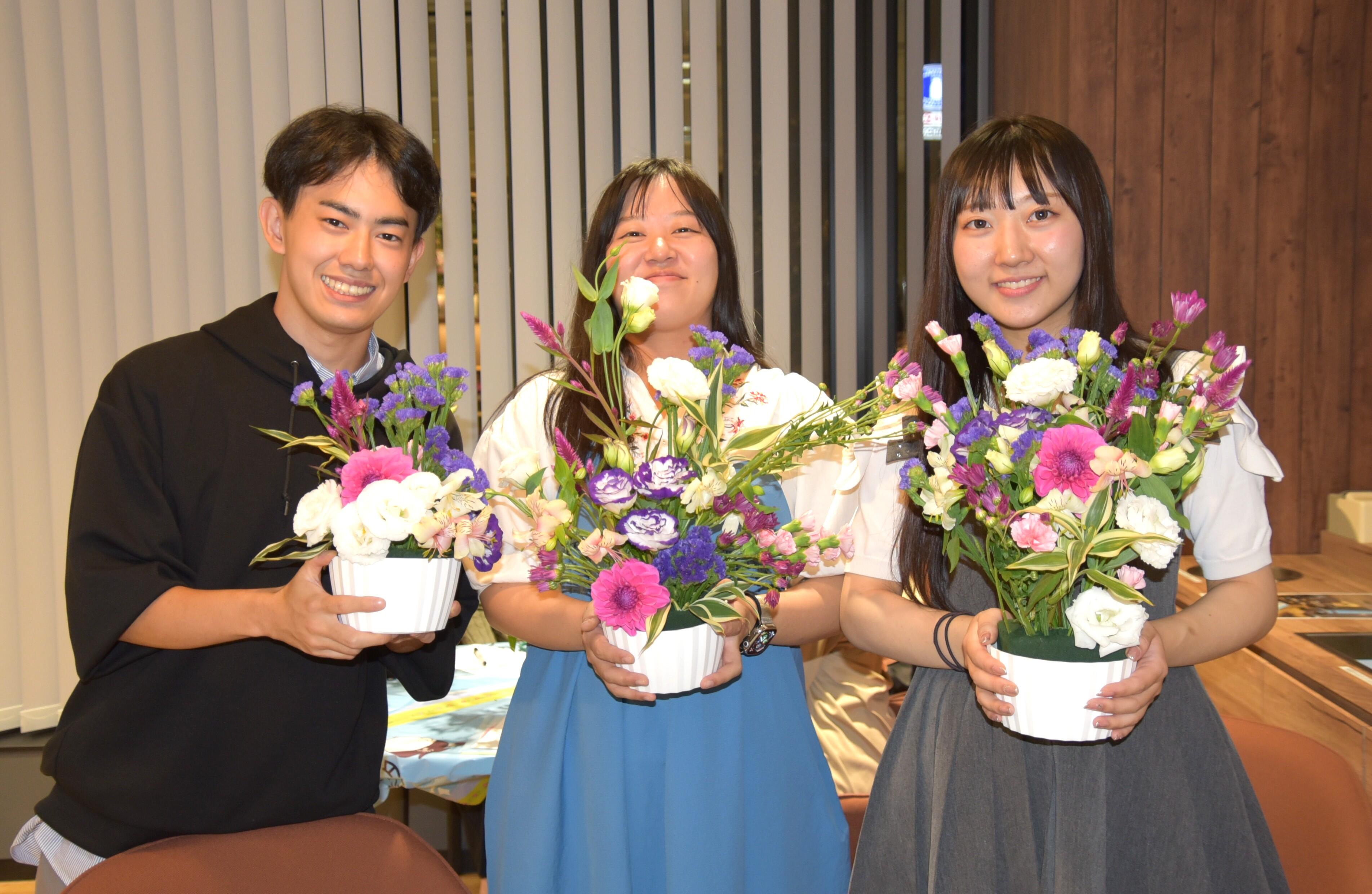 完成したフラワーアレンジメント作品を手にする和田さん（中央）ら