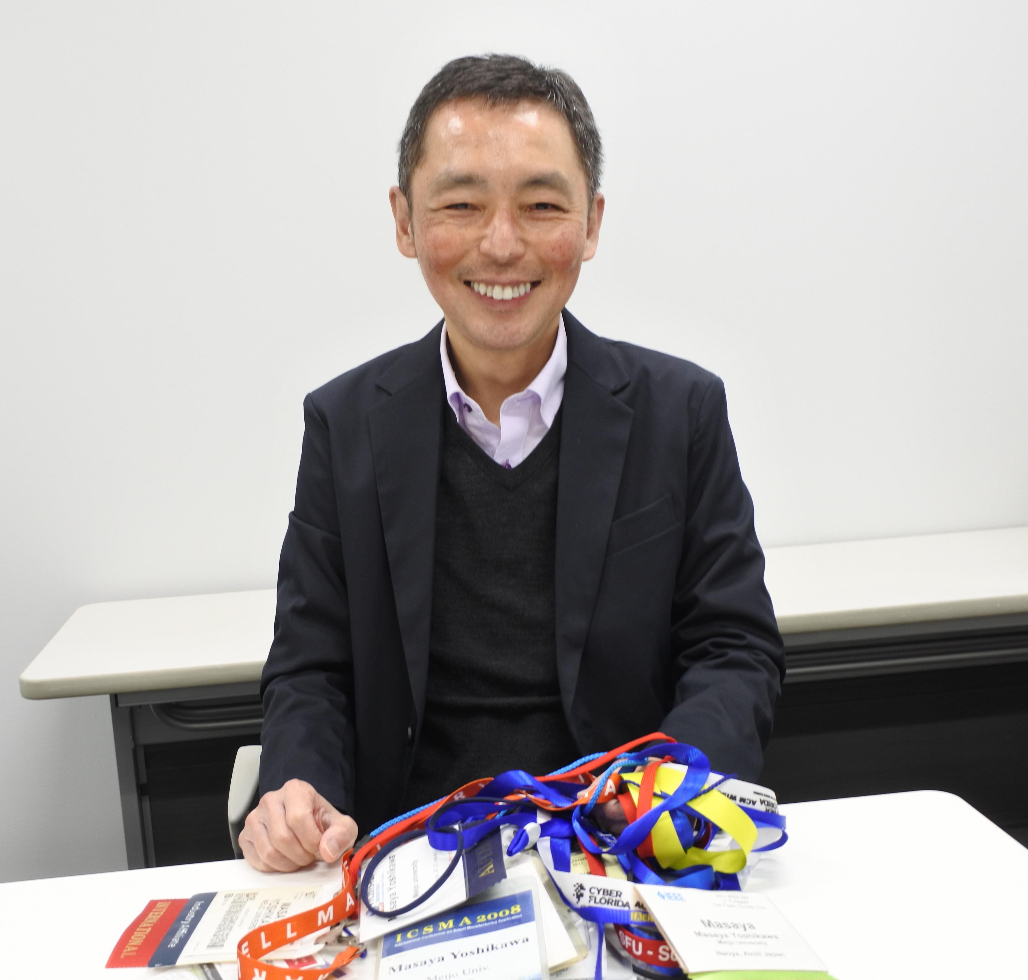 海外の学会で首にさげた名札を手にする吉川雅弥教授